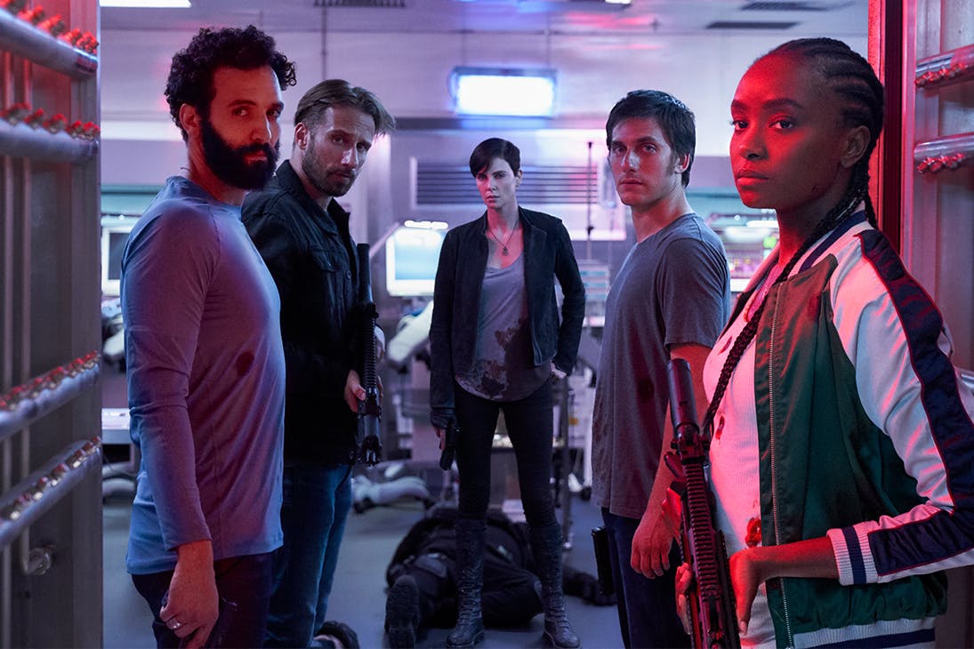 a group of men and women, armed with weapons, stare down the camera